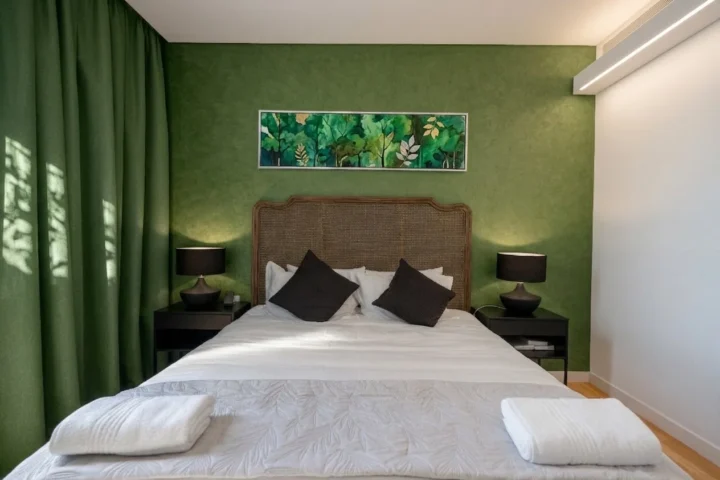 Camera da letto con parete verde e testiera in rattan